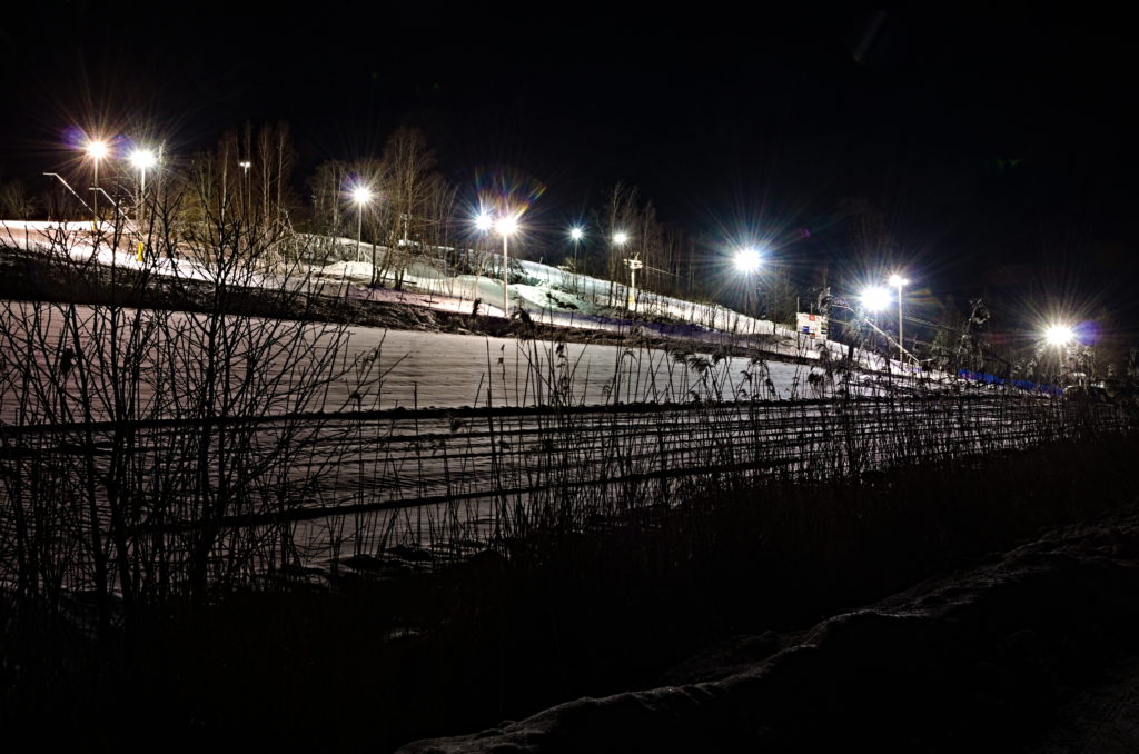 Germundö Alpin sedd från parkeringen i mörker med belysningen tänd över nedfarterna, Åland.